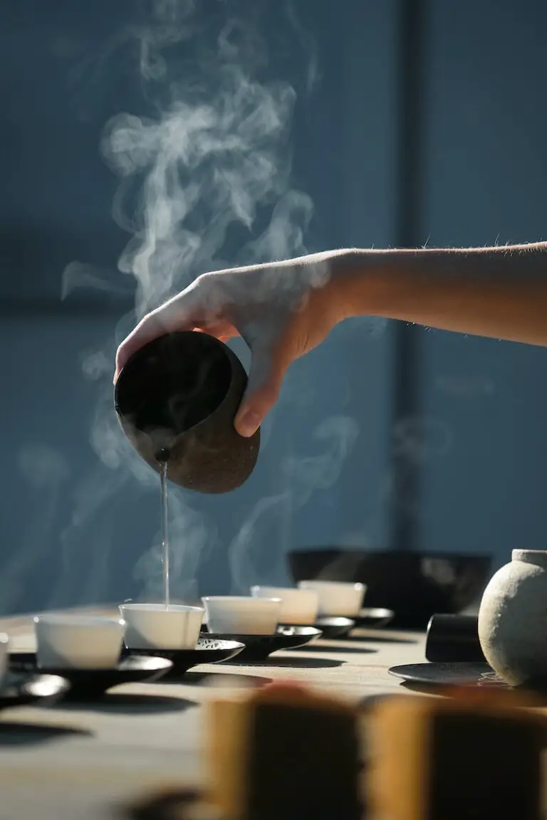 person pouring hot tea on white cups