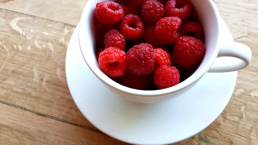 raspberries on white ceramic mug with saucer