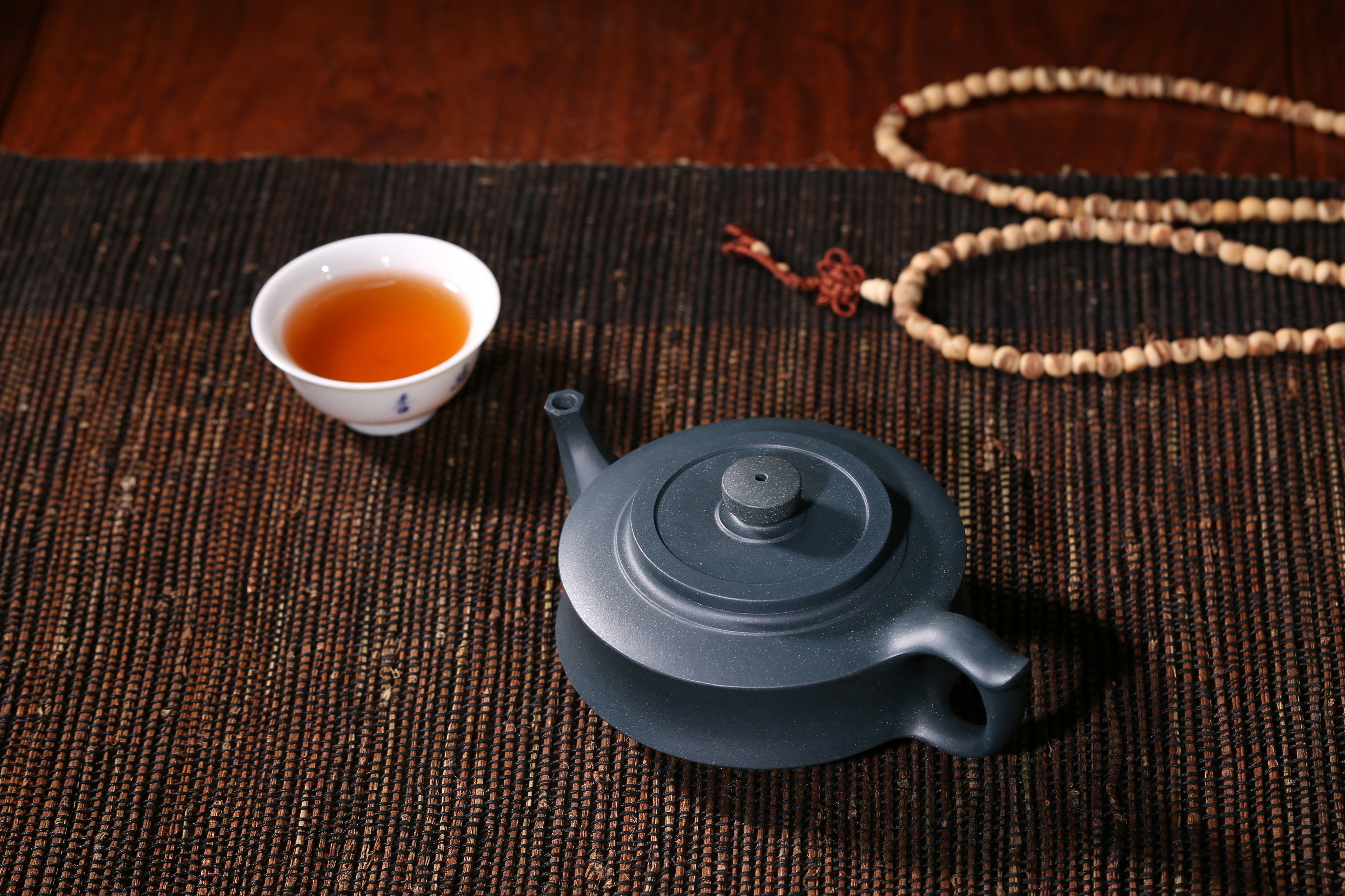 white ceramic teacup beside black ceramic teapot