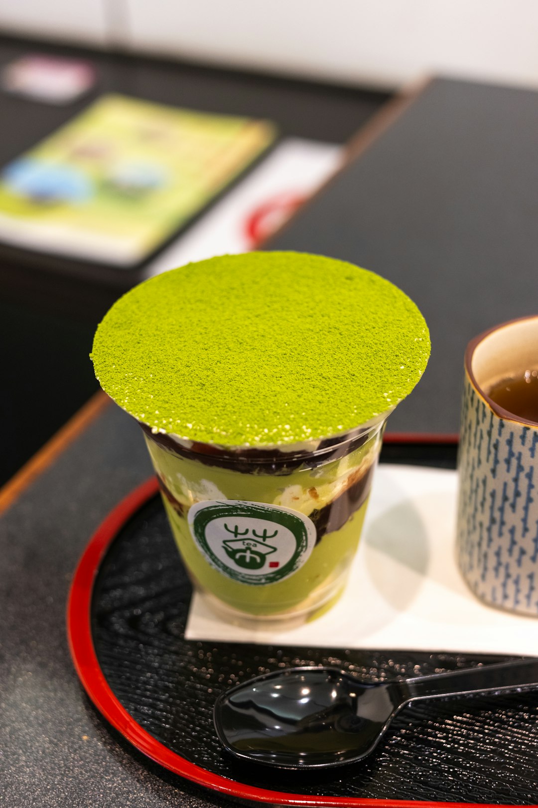 a cup of green tea and a spoon on a tray